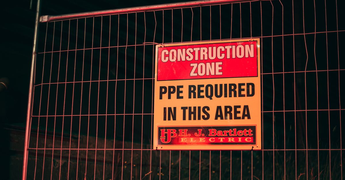 Bright construction warning sign indicating PPE requirement at night.