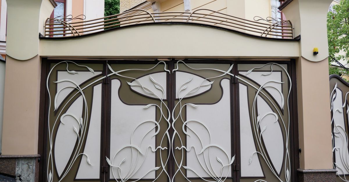 Elegant Art Nouveau gate with intricate floral design in a city architecture setting.