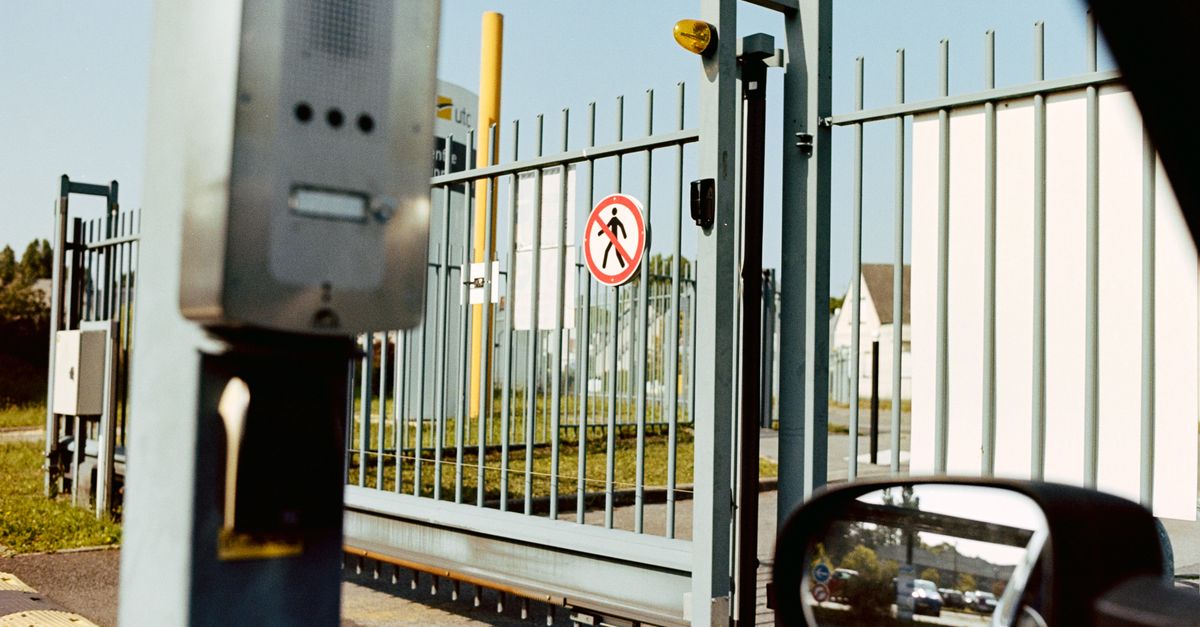 Security gate with no pedestrian sign and intercom, view from a car window.