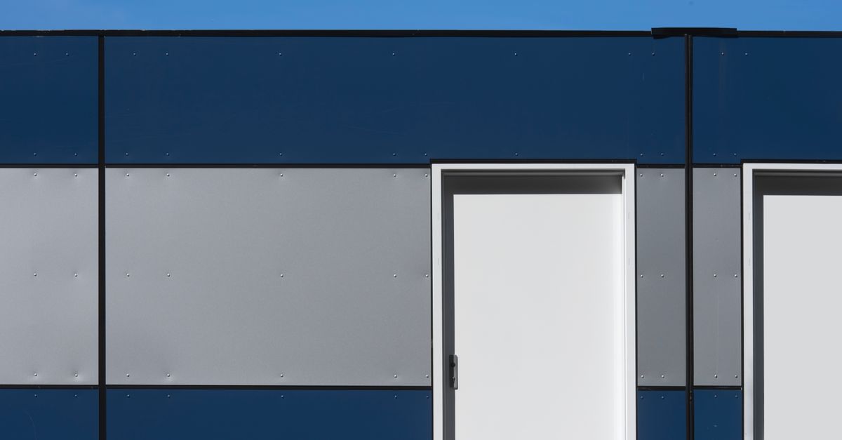 Modern minimalist architectural design featuring blue and gray panel facade with white doors.