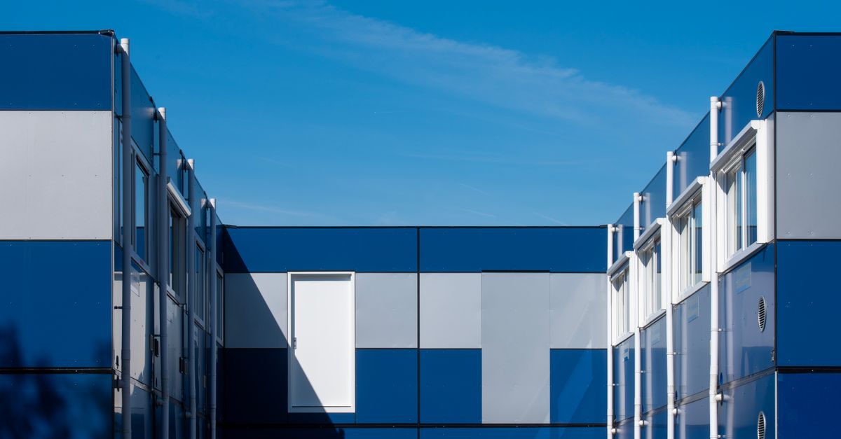 Distinctive modular building with blue panels under a clear sky, showcasing geometric design