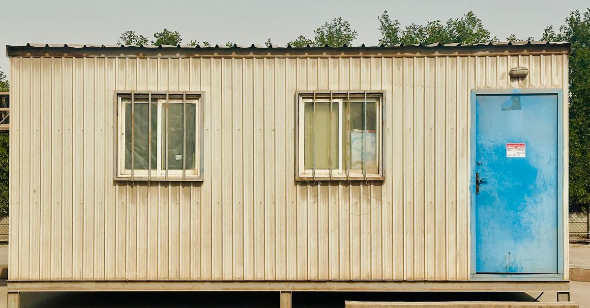 A portable cabin with a distinctive blue door in a sunny outdoor setting in Saudi Arabia.