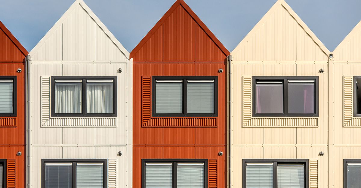Contemporary row houses with vibrant color palette under a clear sky, showcasing modern architecture.