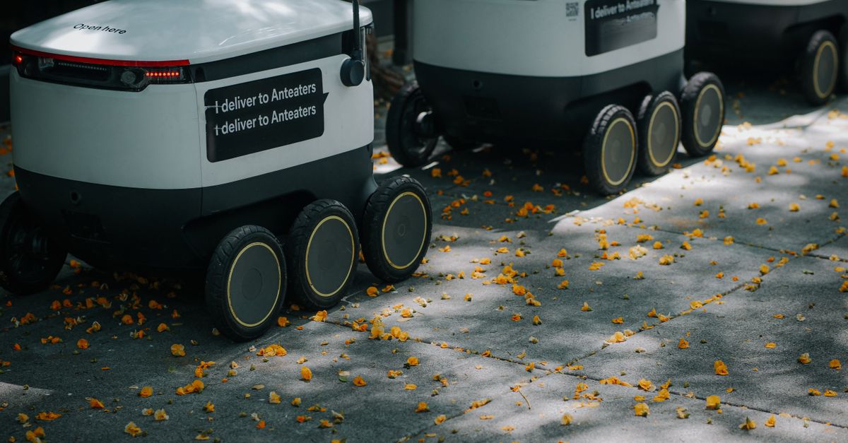 Futuristic delivery robots navigating a leaf-strewn sidewalk, showcasing innovation in modern urban logistics.