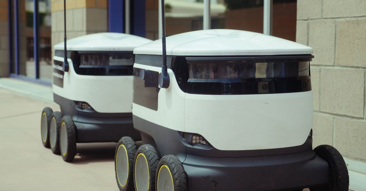 Two autonomous delivery robots positioned outside a modern building, showcasing innovation in robotics and mobility.