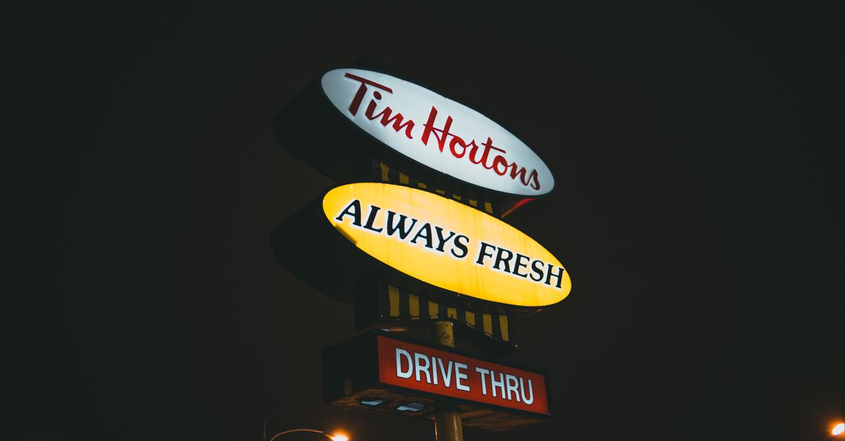 Low angle of signboards with inscriptions against streetlights under dark sky in city at night