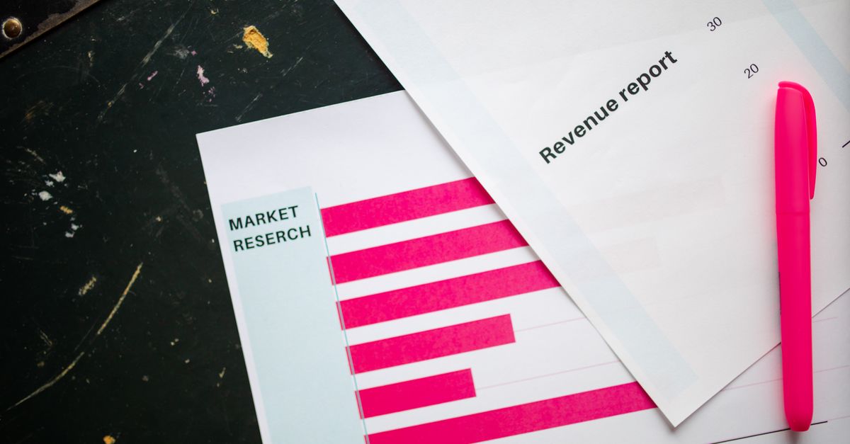 Close-up of market research charts and a revenue report with a pink pen on a desk.