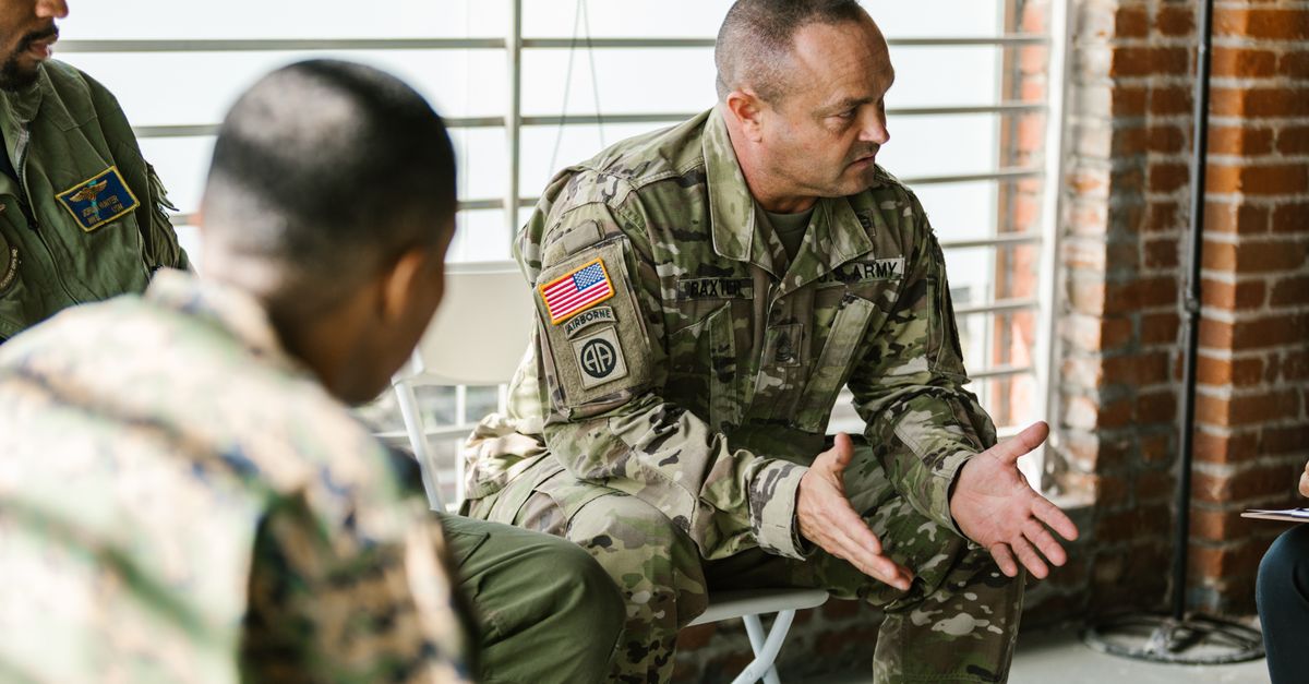 Military veterans engaging in a supportive group therapy session indoors.