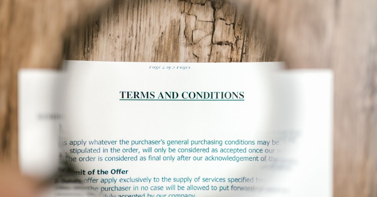 Magnifying glass focusing on terms and conditions document on wooden surface.