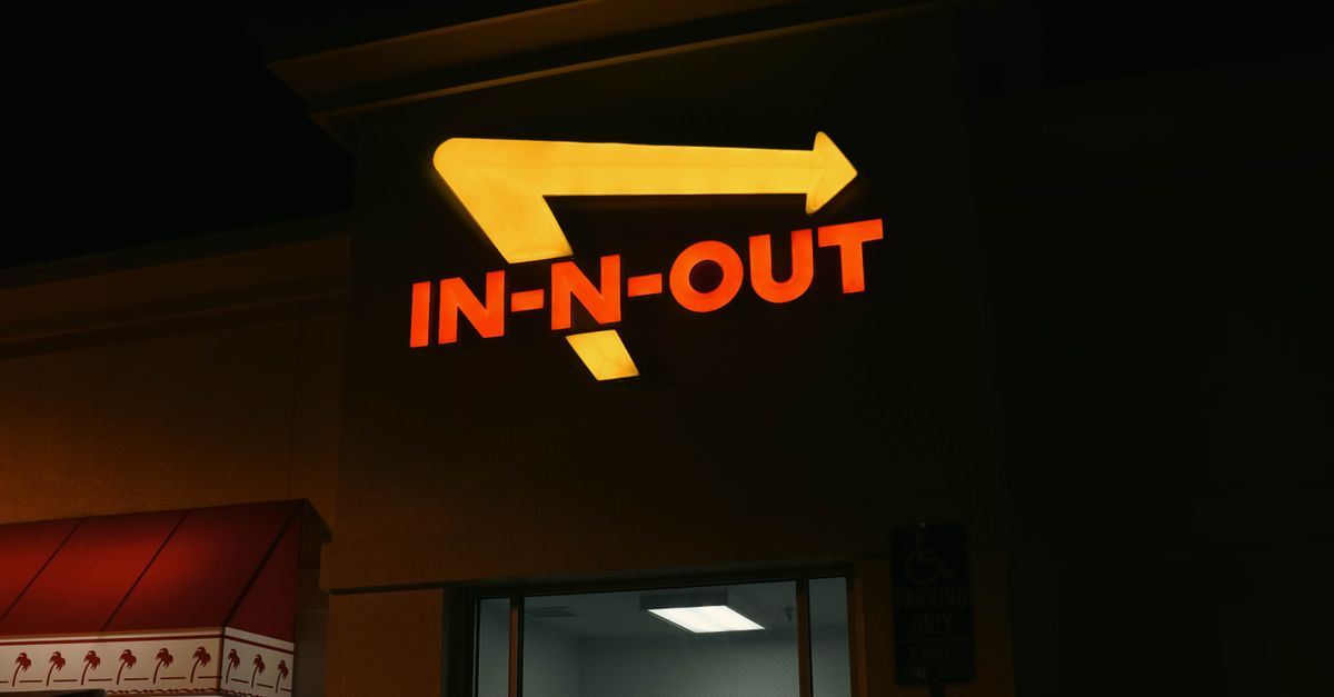Bright neon In-N-Out sign glowing at night outside a restaurant in California.