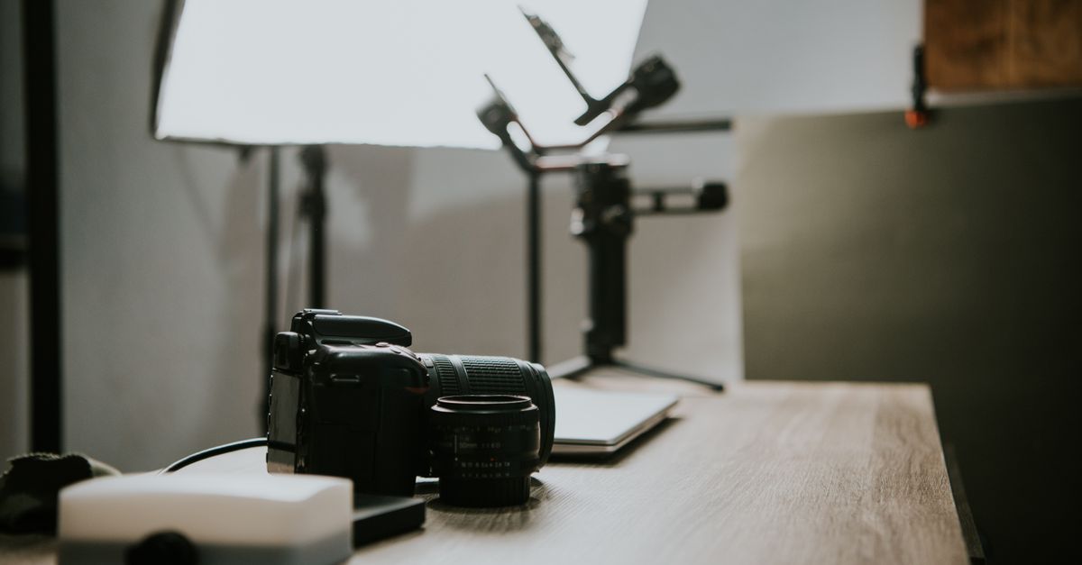 Close-up of a DSLR camera and lens on a wooden table in a studio setting, perfect for photography-themed content.