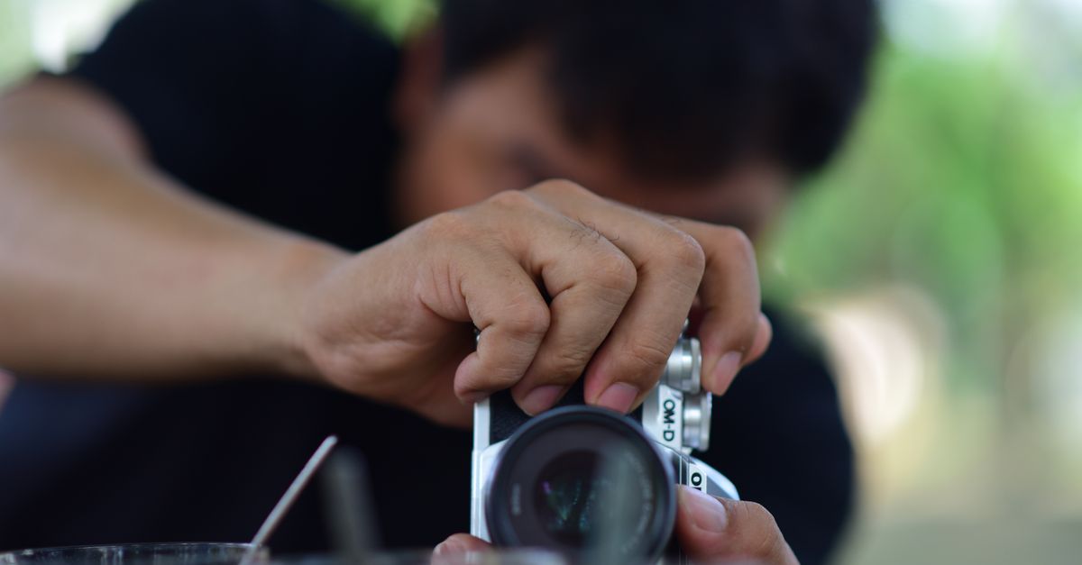 Photographer using a camera capturing a moment with precision. Blurred background.