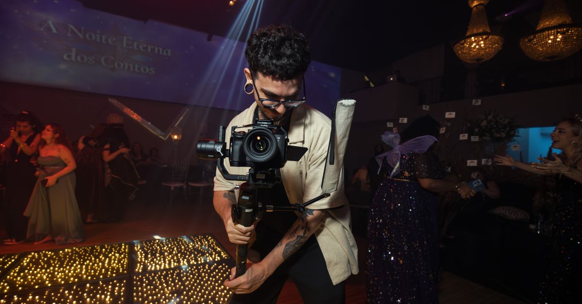 A skilled photographer filming an elegant party with vibrant lighting and dressed-up guests.