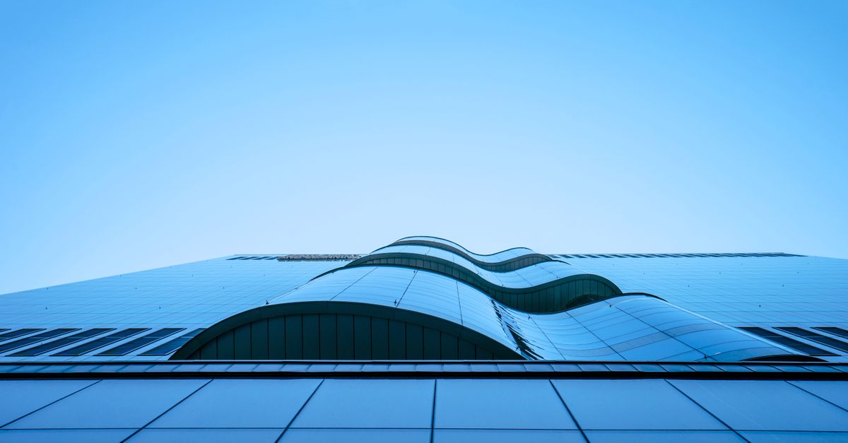 Architectural photograph capturing a modern glass building with elegant curved lines and steel structure.