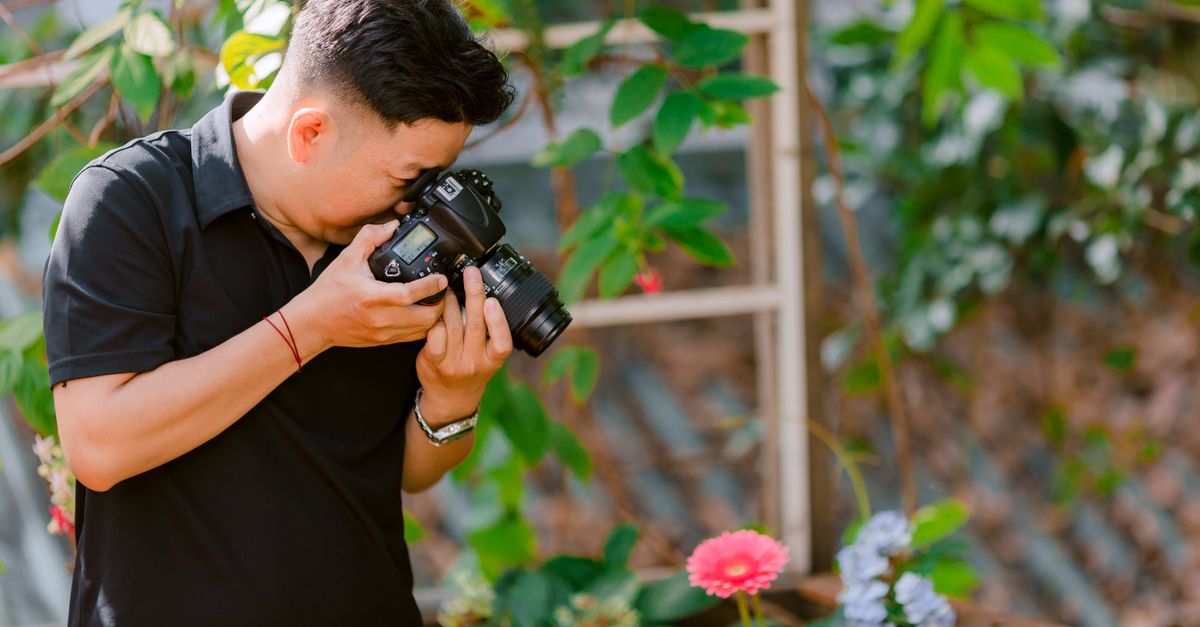 Photographer focused on capturing vibrant garden flowers outdoors.