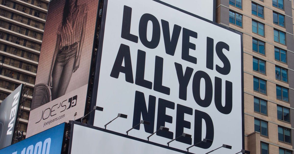 Large city billboard reads 'Love Is All You Need' in New York City street.