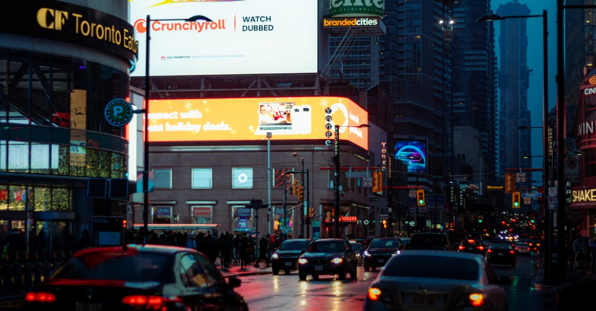 Dynamic city street scene in Toronto with vibrant billboards and bustling traffic.