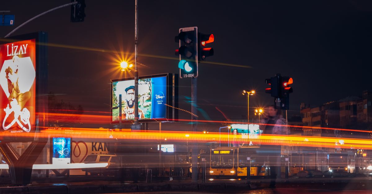 A vibrant city street scene captured at night with long exposure showing traffic lights and light trails.