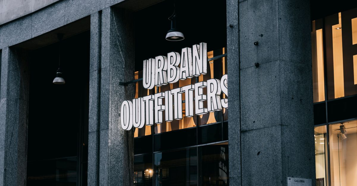 Urban Outfitters store entrance with illuminated signage in a city environment.
