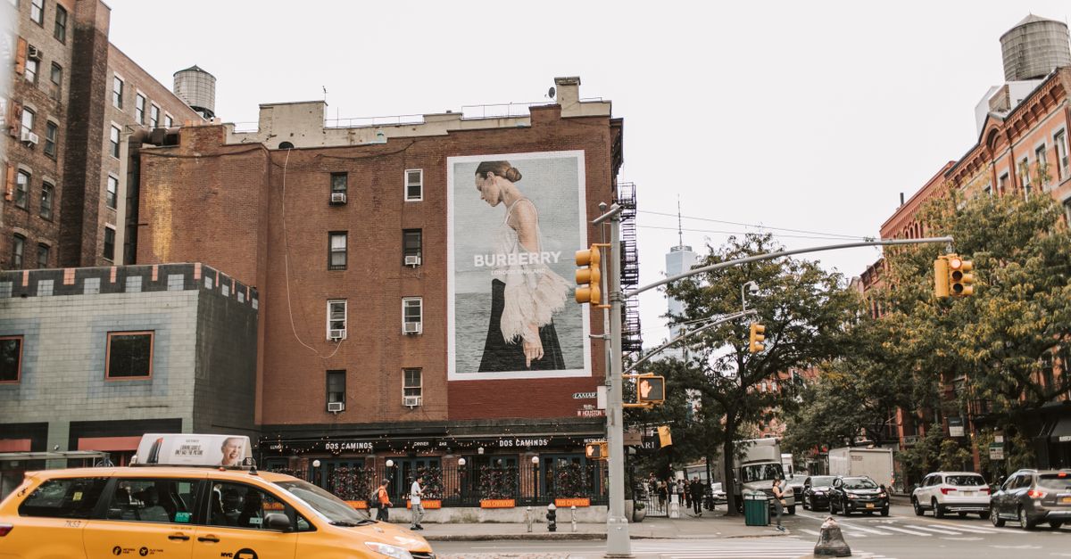 Vibrant street view in New York City featuring a Burberry advertisement on a brick building.