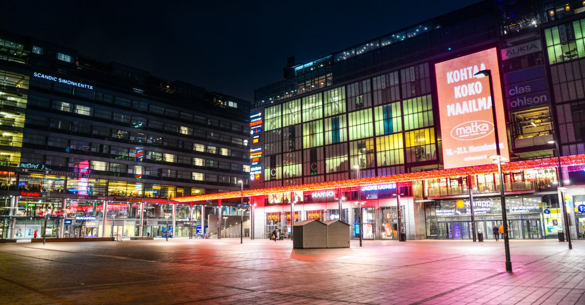 Illuminated city square at night showcasing modern architecture and vibrant signage.