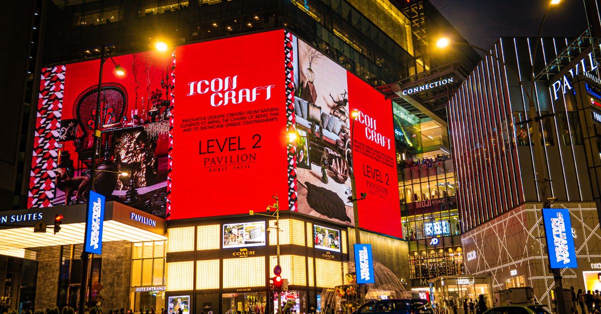 Vibrant nighttime view of Pavilion Kuala Lumpur with bright digital displays and pedestrians.