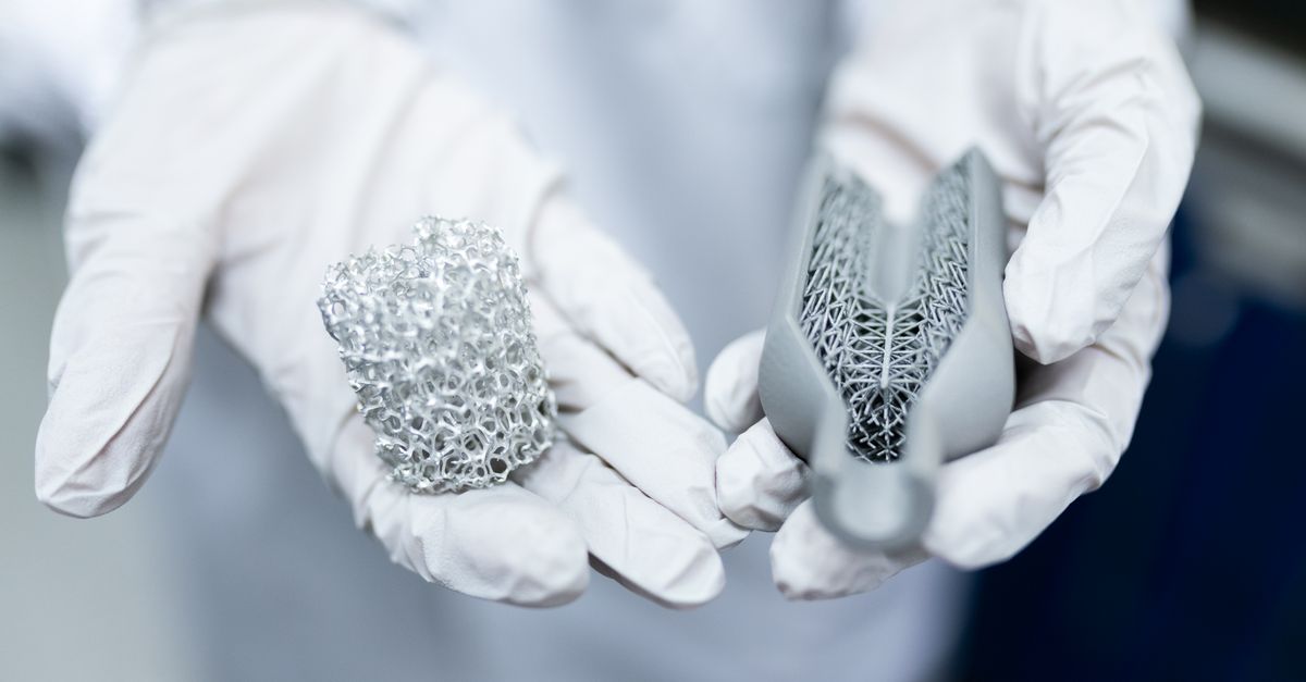 Laboratory setting showing gloved hands holding innovative 3D printed metal structures.