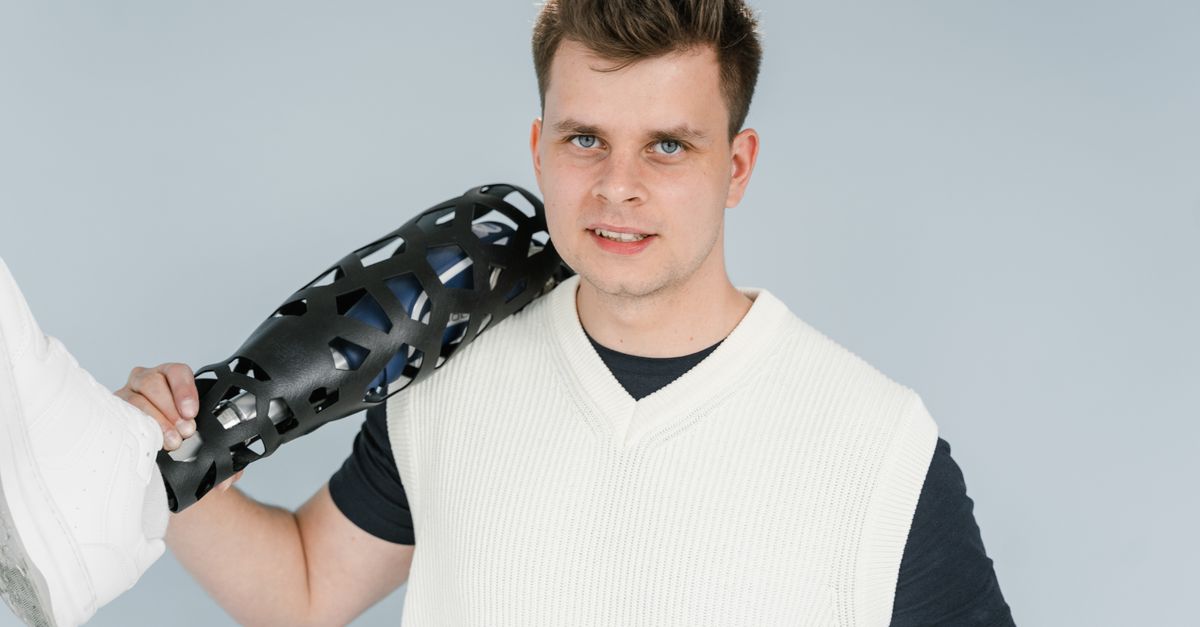 A young adult holding a modern prosthetic leg during a studio photo shoot.