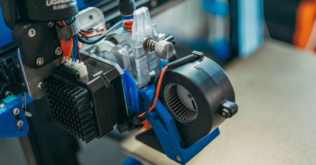 Detailed view of 3D printer parts showing wires and equipment in a workshop setting.