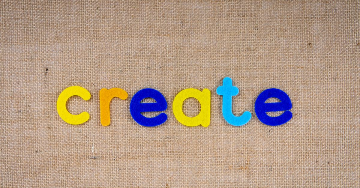 Colorful felt letters spelling 'create' on a burlap background, capturing creativity concept.