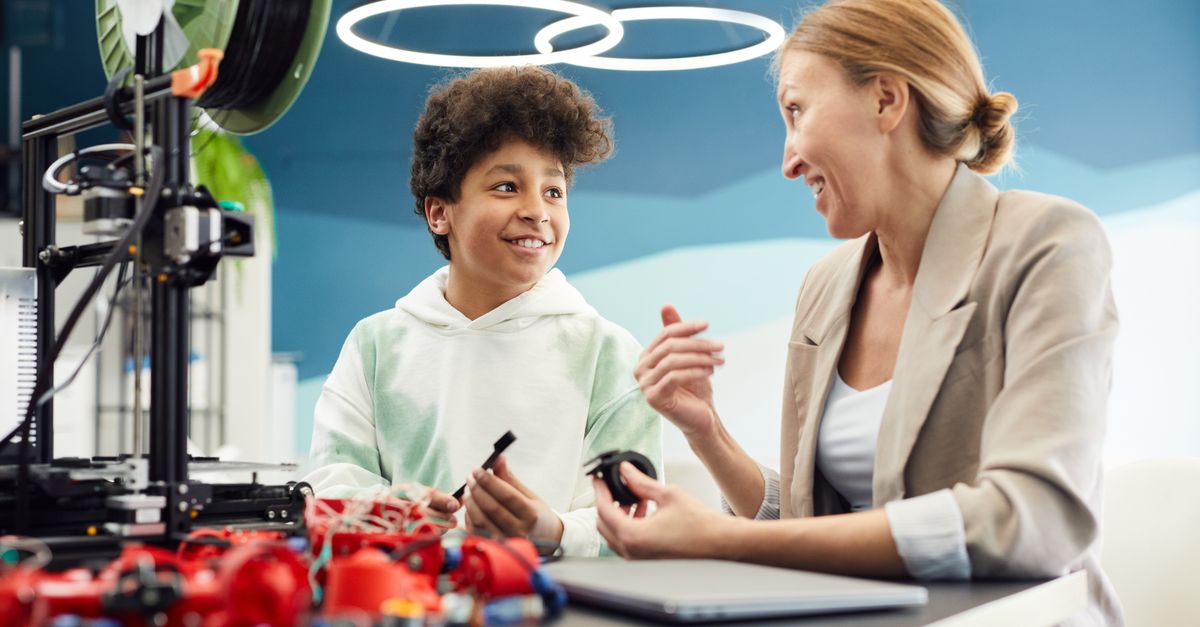 Smiling young male engineer sitting at table with woman and discuss project together while looking at each other in light room