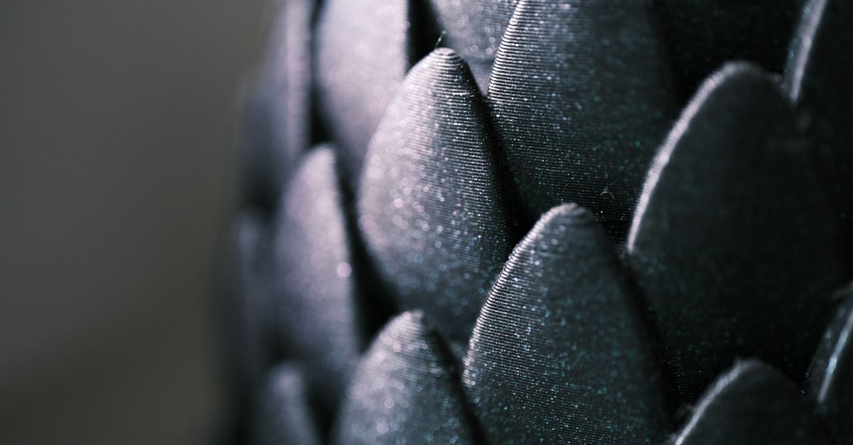 Intricate close-up of glossy black scale-like pattern with a captivating texture and shimmer.