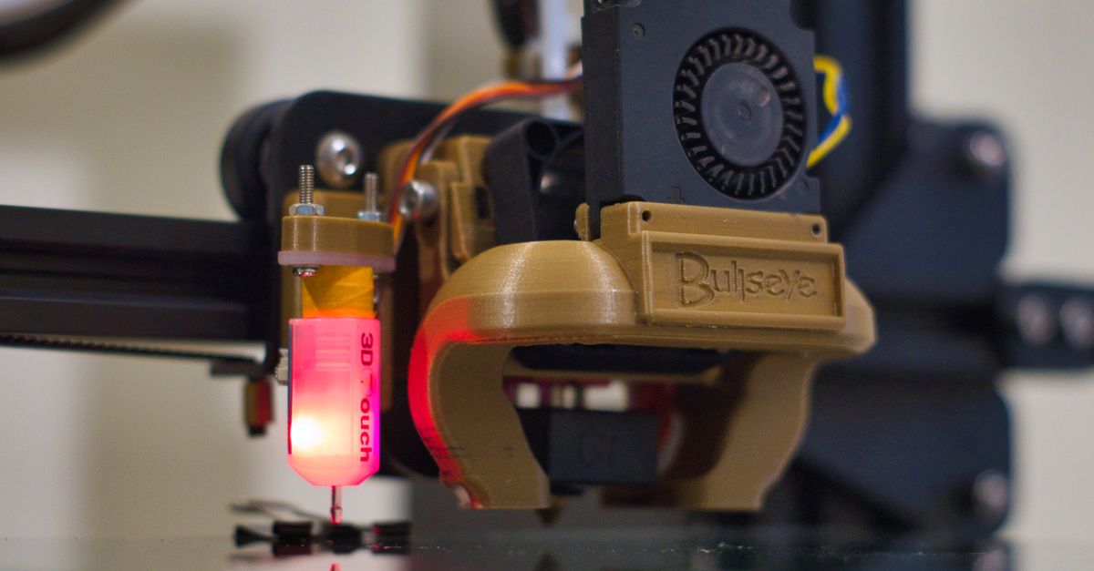 Detailed shot of a 3D printer nozzle operating in a workshop setting.