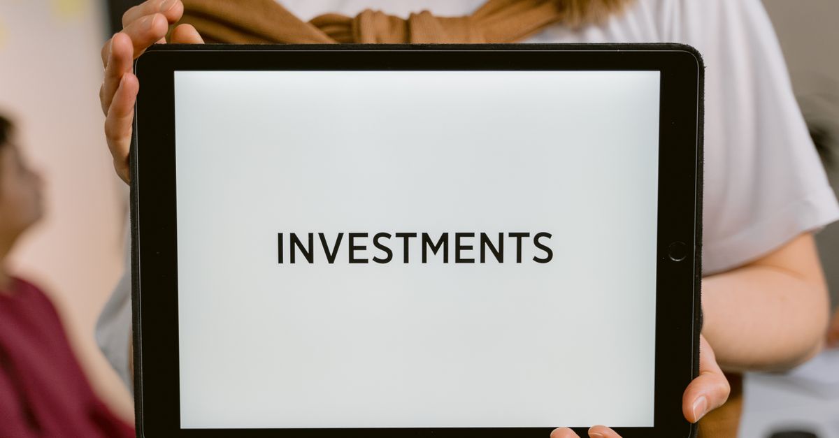 Close-up of a tablet with the word 'Investments', held by a person. Ideal for financial topics.