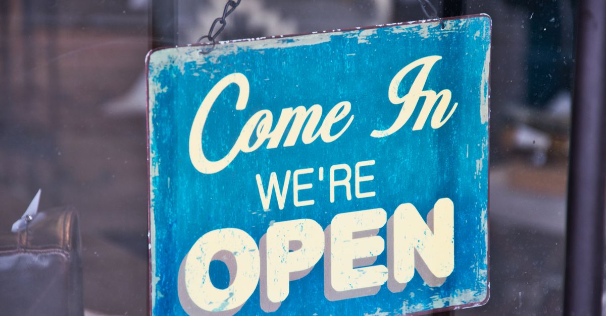 Retro blue open sign on a shop glass door inviting customers in.