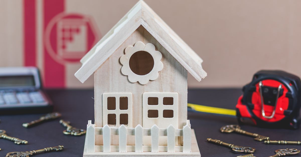 A charming wooden miniature house surrounded by antique-style keys, ideal for concepts of home ownership.