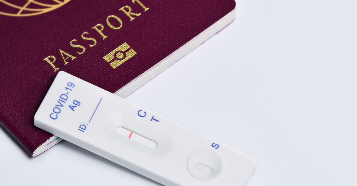 Close-up of a passport and COVID-19 rapid antigen test kit on a white background, symbolizing travel amid a pandemic.