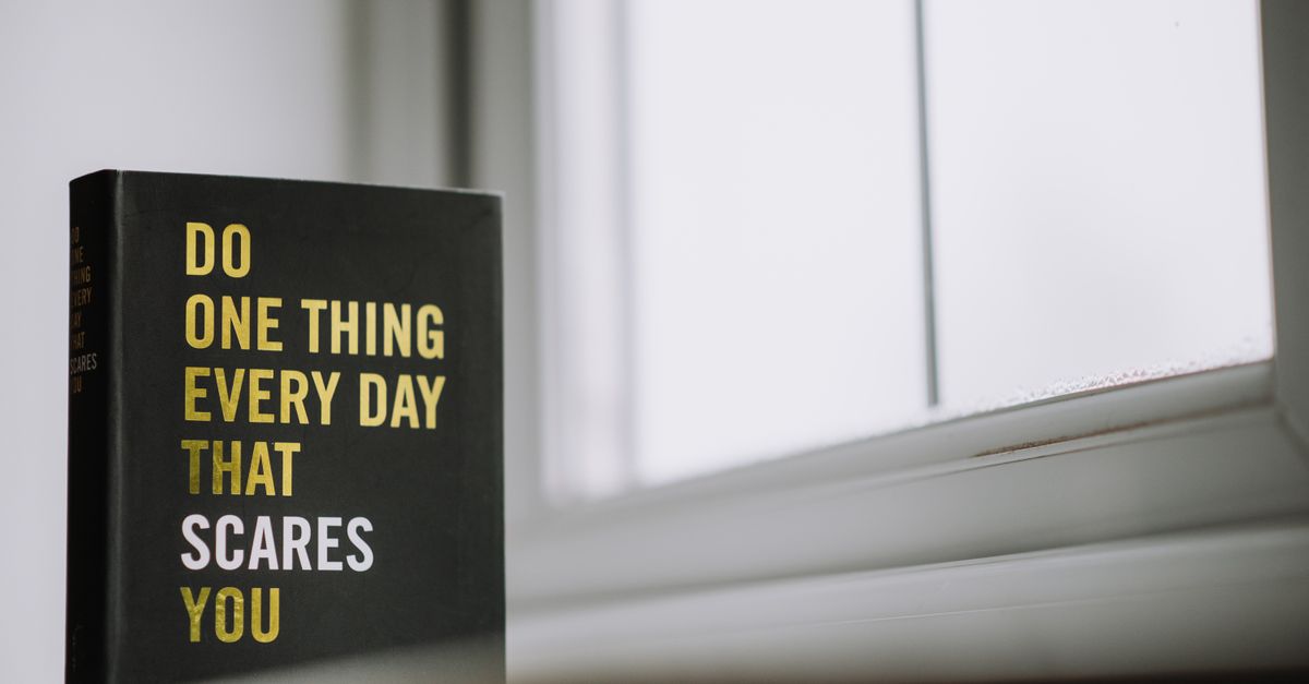 Rectangular shaped book with printed title on black hardcover on windowsill in house in daytime
