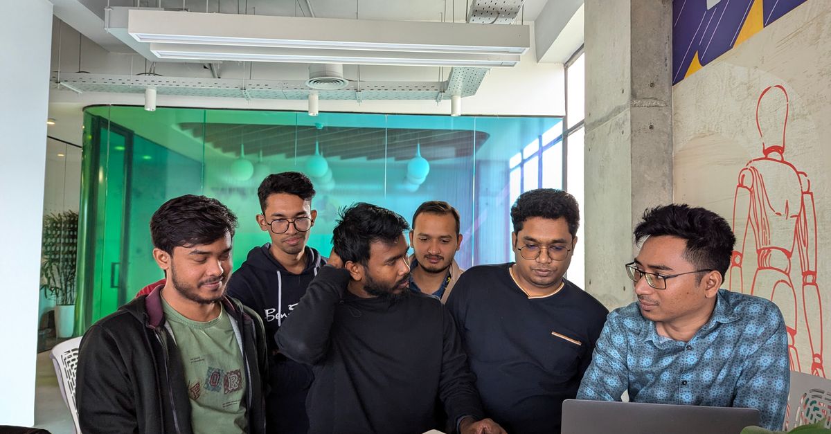 A group of coworkers collaborating with laptops and notebooks in a modern office space.