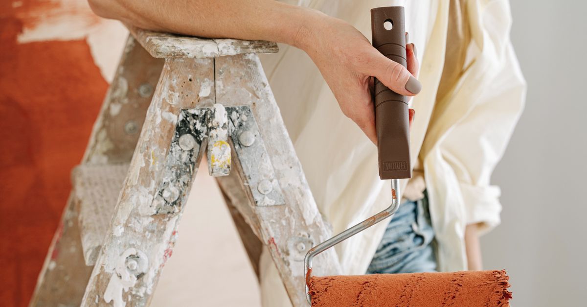 A close-up of a person using a roller to paint a wall during renovation.