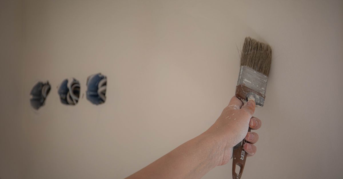 A person painting a wall with a brush, showcasing a home makeover process.
