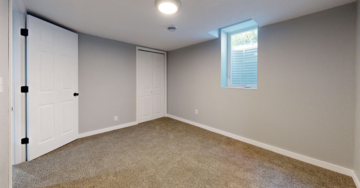 Empty room with carpet flooring, white doors, and a window. Ideal for real estate listings.