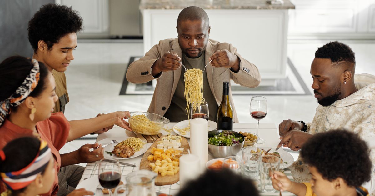 A warm family gathering enjoying dinner together with wine and pasta.
