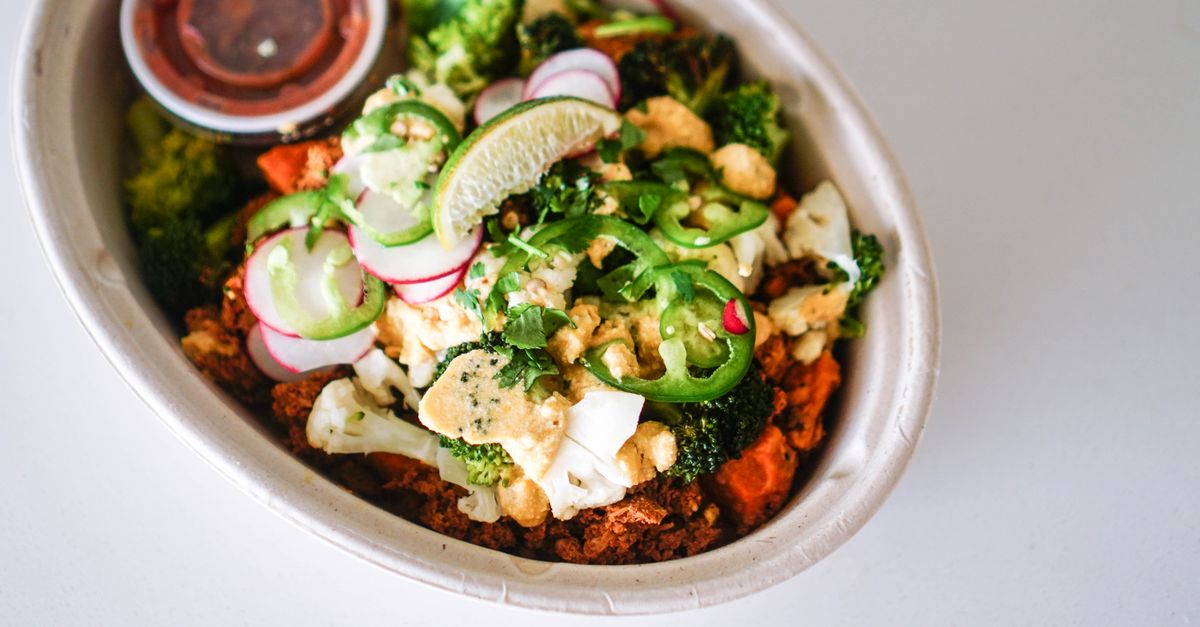 Colorful bowl of fresh vegetables with sliced lime, jalapenos, and radishes, showcasing a healthy meal option.