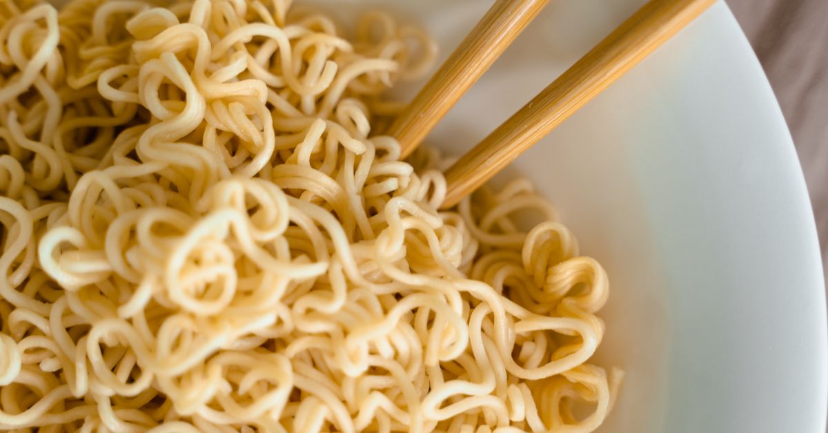 Tasty close-up of cooked noodles in a bowl with chopsticks for an Asian dining experience.