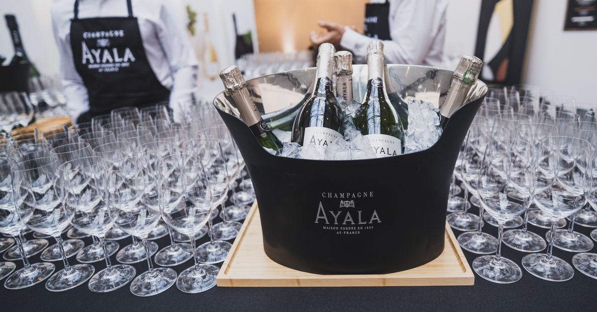 Chilled champagne bottles in ice bucket surrounded by empty wine glasses at elegant indoor event.