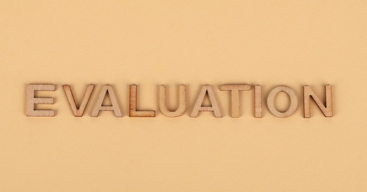 Wooden letter blocks arranged to spell 'evaluation' on a beige background.