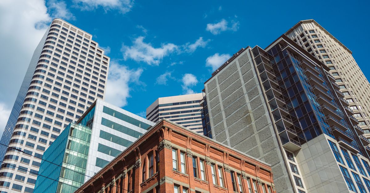 Low-angle view of diverse architecture with modern skyscrapers against a blue sky.