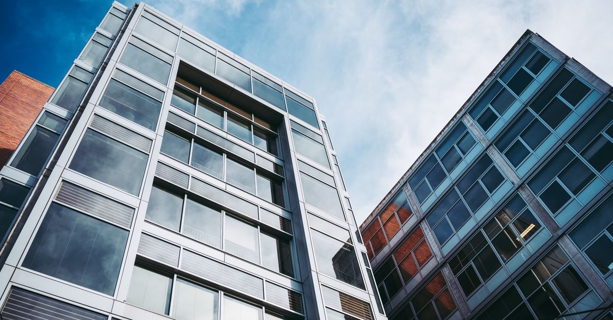 From below of facades of modern buildings in residential district under cloudy blue sky in daytime