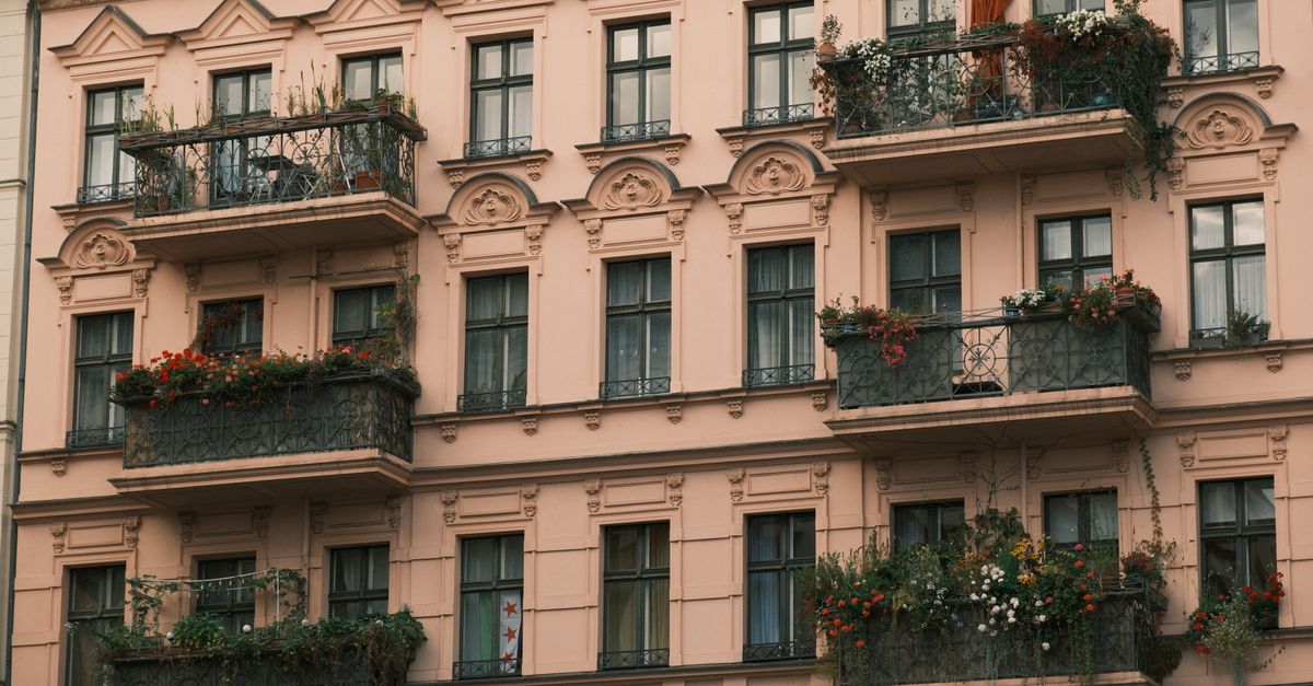 A detailed view of a European-style apartment building with ornate balconies decorated with plants.